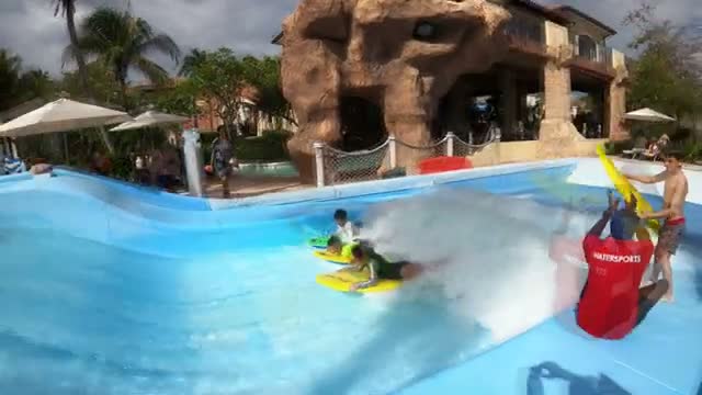 Kids riding the FlowRider on bodyboards