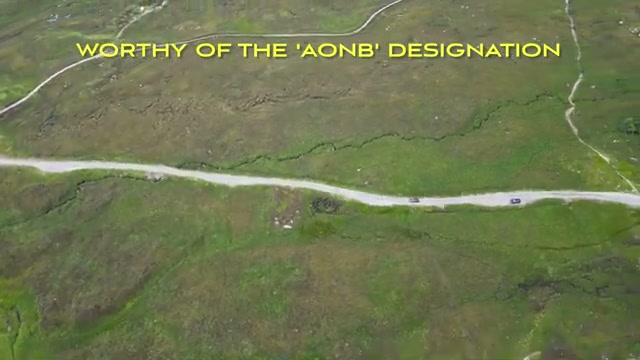 A lone mountain road crossing open moorland from the drone