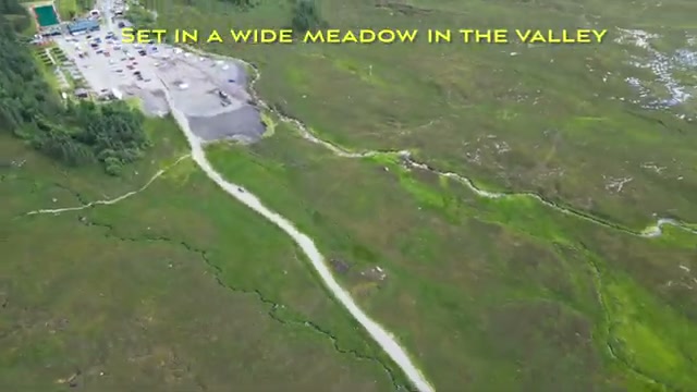 The Three Sisters car park set in a wide meadow in the valley, seen from the drone