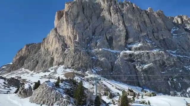The towering rock face of Sassolungo against a blue sky