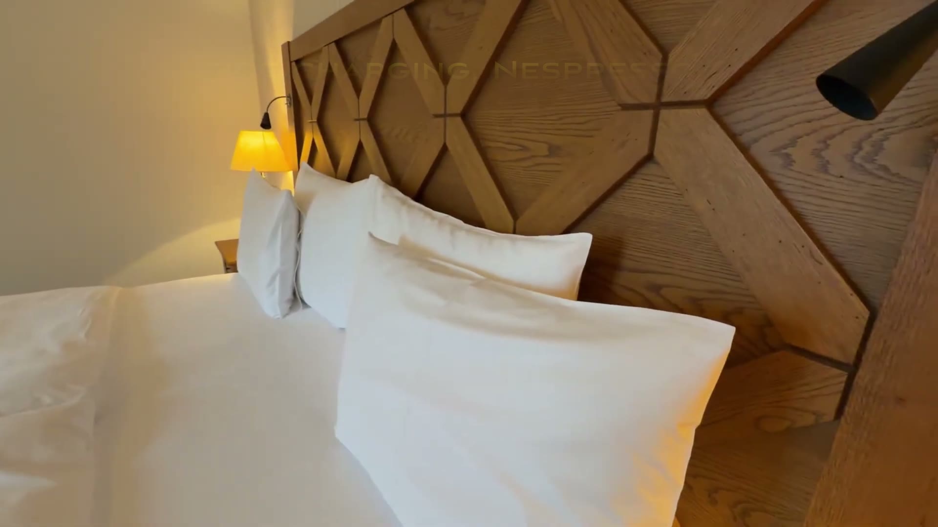 King bed with white bedding and a geometric wooden headboard in our Kempinski suite