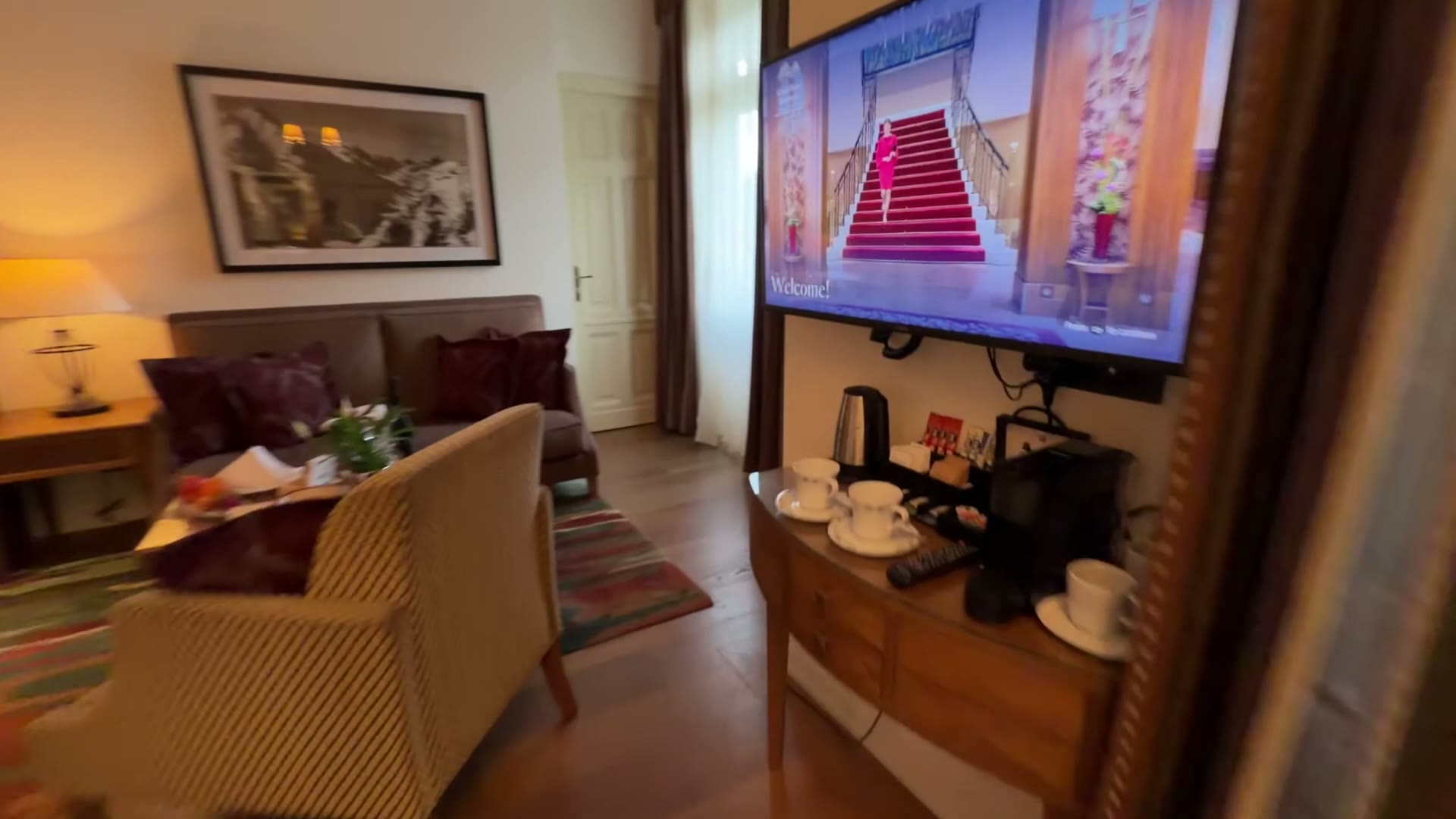 Sofa, armchair and coffee table in the suite living area, with a television and tea and coffee setup
