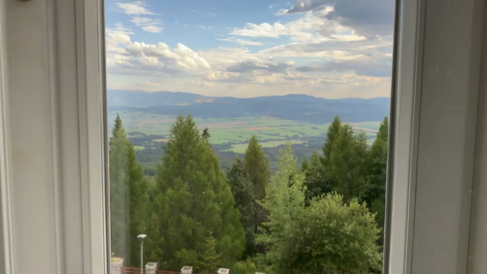 Trees, open countryside and distant hills seen through the valley-facing suite window