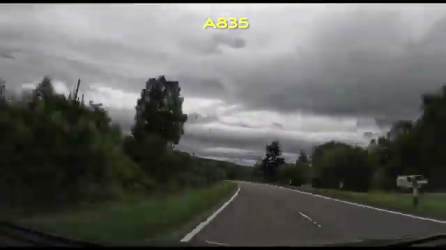A tree-lined stretch of the A835 under moody dark clouds