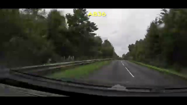 The A836 lined with a guardrail and dense trees on both sides