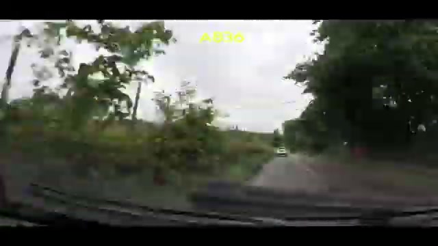 A narrow wooded stretch of the A836 with a car ahead