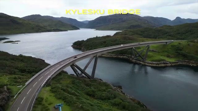 Aerial view of Kylesku Bridge curving across a sea loch with mountains beyond
