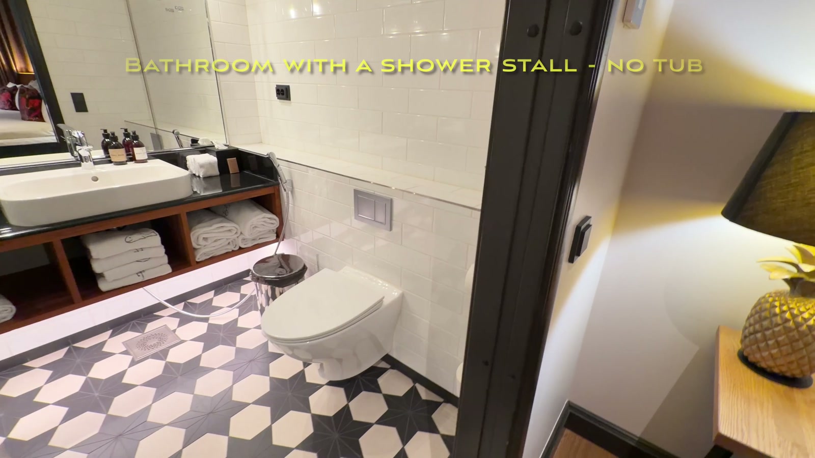 Bathroom with a glass shower stall and geometric black-and-white floor tile
