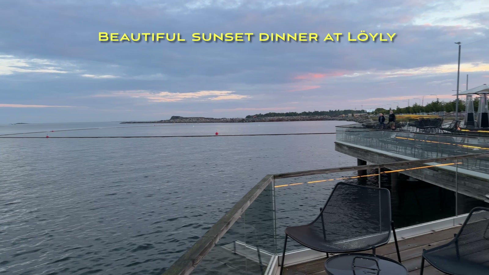 Loyly’s waterfront deck at dusk, with heaters and umbrella-covered seating over the water