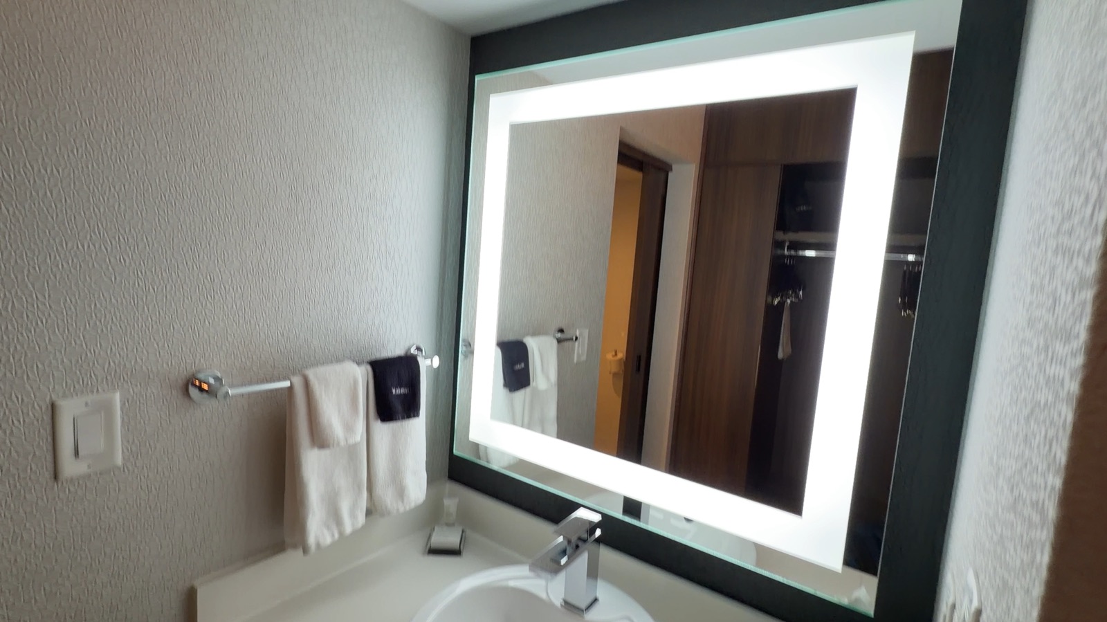 Bathroom vanity with lit mirror and closet