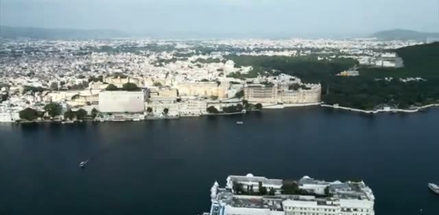The old city of Udaipur packed in behind the palace, with green hills across the lake