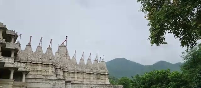 A side view of the carved shikhara spires against the hills