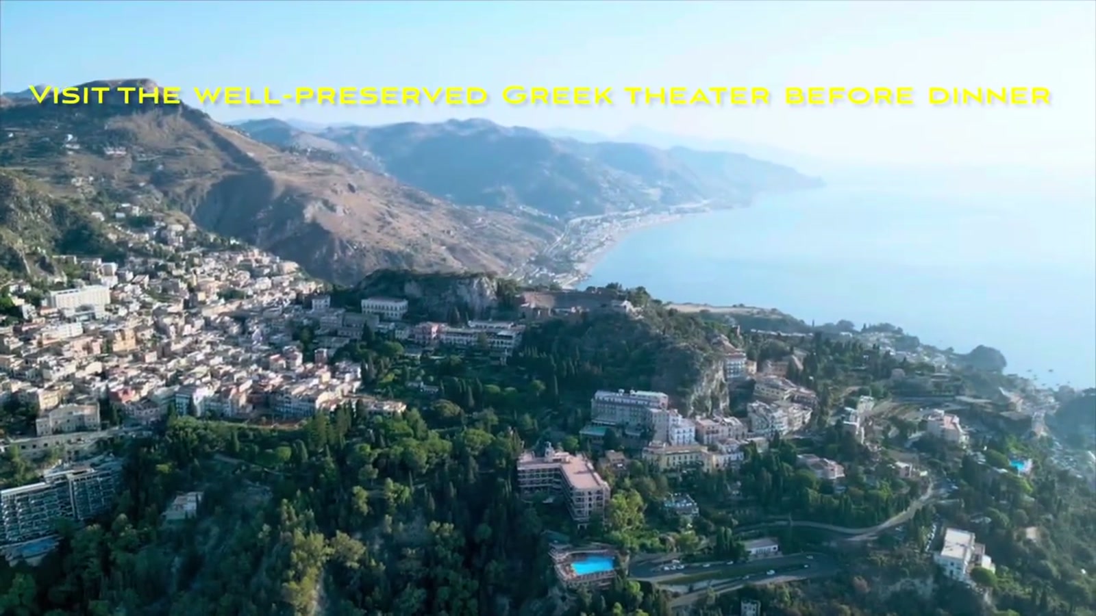 Aerial view of Taormina and its Greek theater, with the coastline stretching toward Naxos
