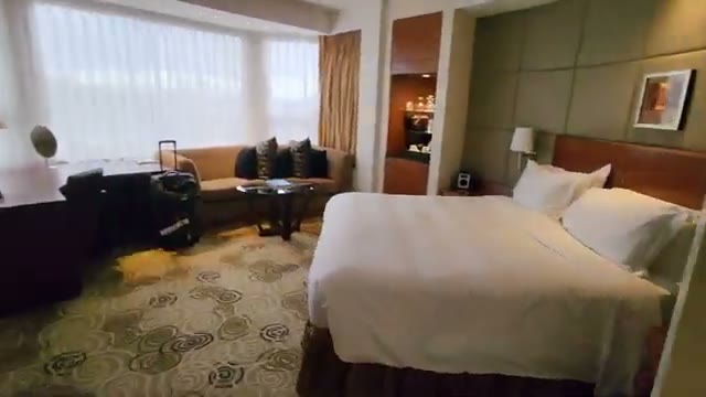 The executive room: bed, sofa seating area, desk, and minibar cabinet